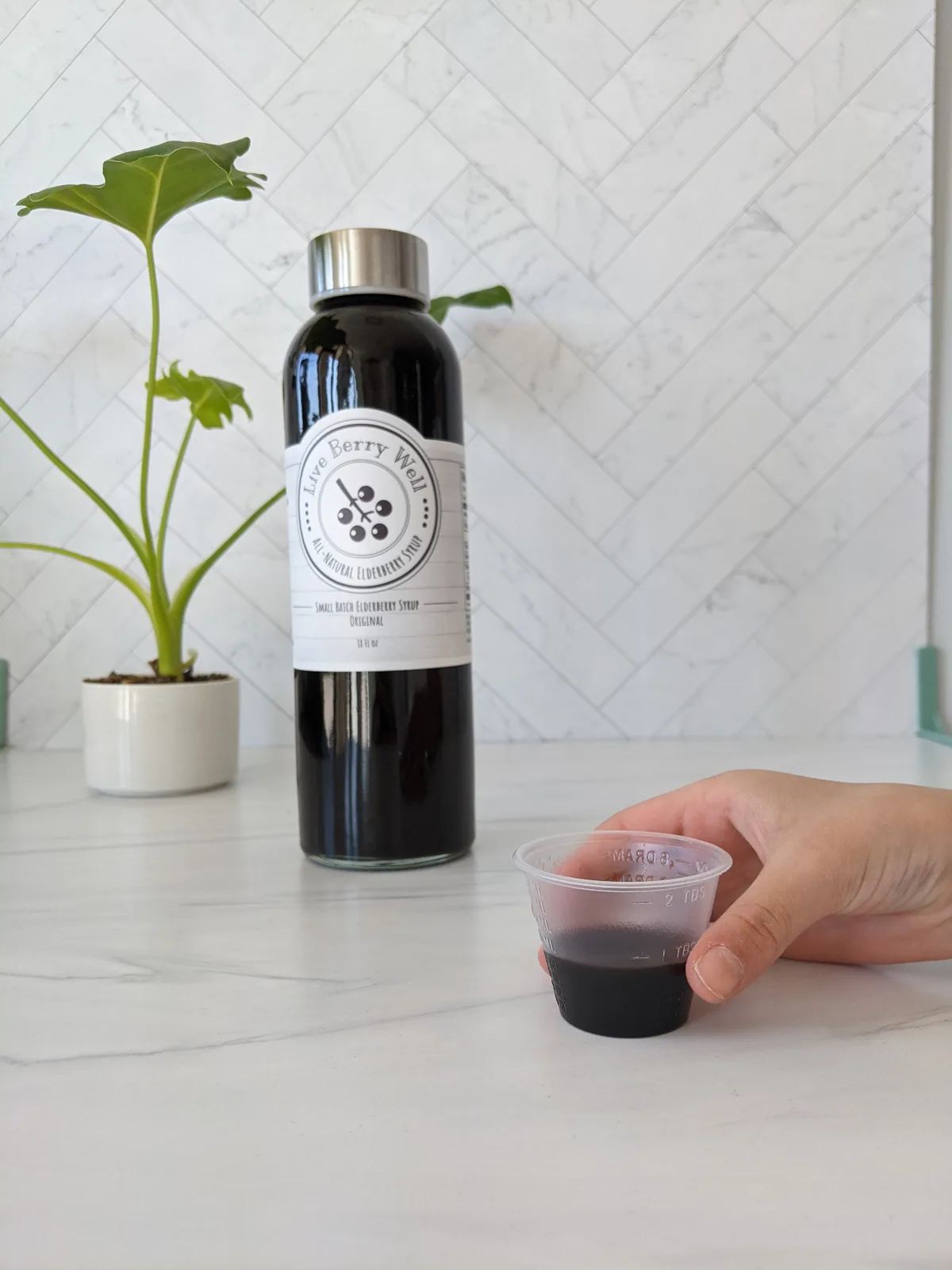 Holding a bottle of elderberry syrup with dosage cup